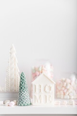 Merry Christmas decoration concept with candles and festive decor, colorful marshmallows, christmas trees on light white background. Cozy home. Space for text.