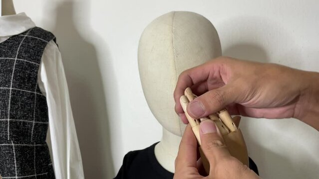 Male hand adjusting child mannequin wooden fingers