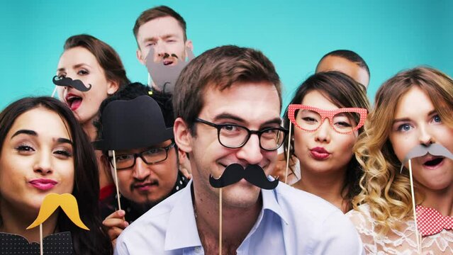 Party, friends and photobooth with a man and woman group in studio on a blue background for fun or celebration. New year, birthday and diversity with a male and female friend bonding at an event