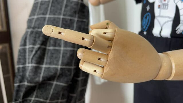 Child mannequin showing a middle finger indoor. Hand gesture concept