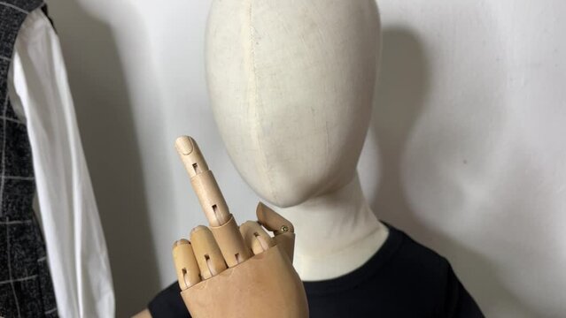 Child mannequin showing a middle finger indoor. Hand gesture concept