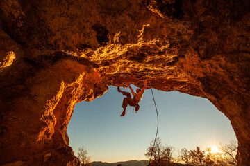 men climbing a cave at sunset with a lot of passion and strength