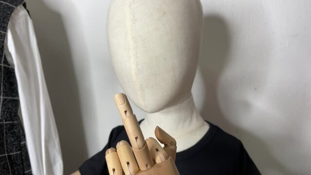 Child mannequin showing a middle finger indoor. Hand gesture concept