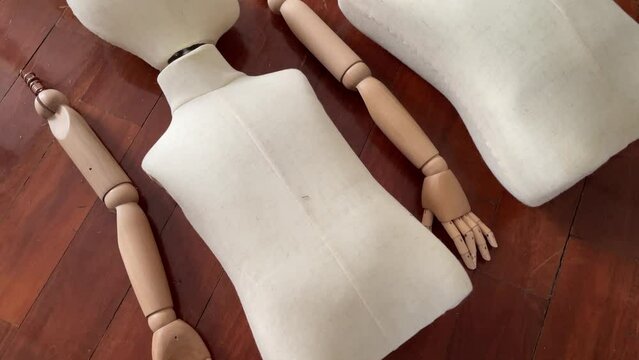 Dismantled child mannequin body parts on wooden parquet floor.