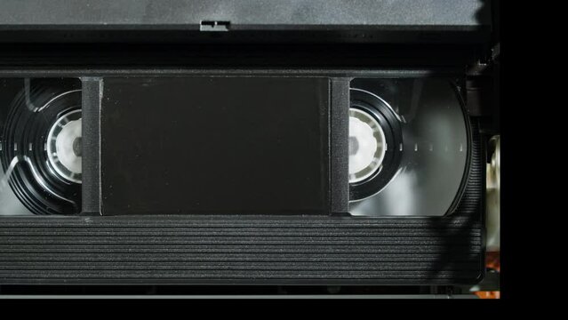 Old video recorder inside close-up, VHS. Retro player in neon red light, vintage video cassette broadcasting, audio tape. 