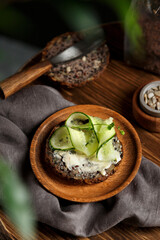 Toast with cream cheese and sliced cucumber on wholemeal bread. Bruschetta, sandwich on plate and wooden background.