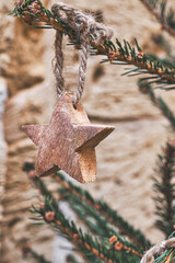 Closeup wooden star on Christmas tree branch. Handmade Christmas zero-waste ornaments
