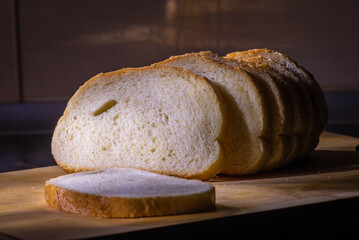 Sourdough slices freshly baked   Sliced loaf of white bread on a chopping board light painting rustic style food.