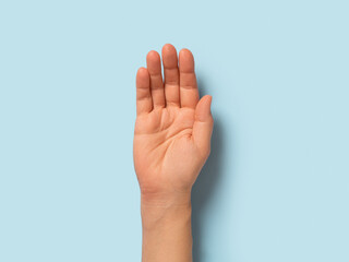 Empty hand palm of caucasian woman over pastel blue background. Open hand gesture close-up. Adult female person right hand macro. Body parts concept.