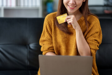 Cute Asian women enjoy using their laptop to shopping online at home and pay their bills with the...