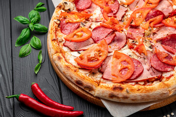 Italian pizza with ham, sausage, mushrooms, tomatoes and onions.