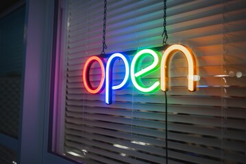 Rainbow color, colorful led lights open sign on a window with blinds
