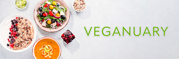 Veganuary banner with prepared dishes and quote veganuary on concrete background