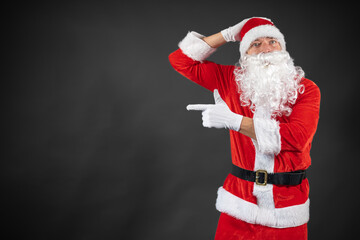 
Portrait von einem verkleideten Weihnachtsmann der auf einen Platzhalter zeigt und isoliert vor grauen Hintergrund ist 