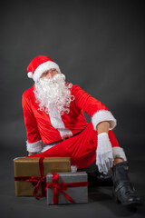 Portrait von einem verkleideten Weihnachtsmann mit einem Geschenk in der Hand vor grauen Hintergrund 