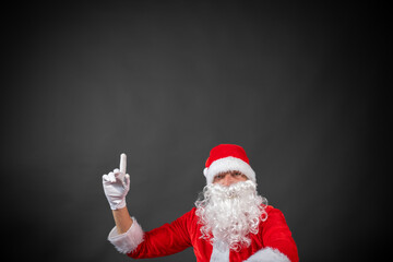 Portrait vom Weihnachtsmann der auf einen Platzhalter zeigt und isoliert vor grauen Hintergrund ist 