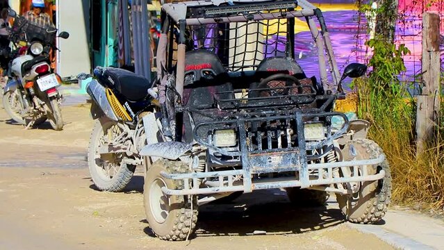 Golf cart buggy cars carts muddy street village Holbox Mexico.