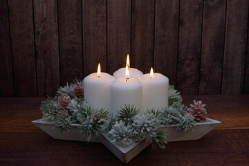 Obraz na płótnie Canvas Adventsdekoration zum vierten Advent: Vier weiße Kerzen mit Tannengrün dekoriert.