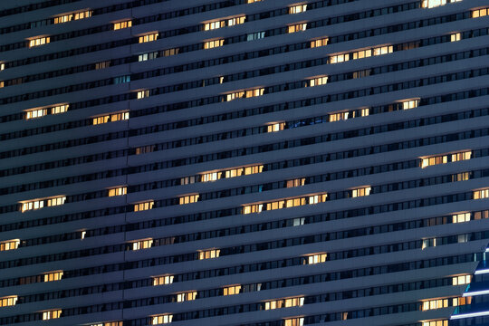 Night facade of high modern building with many illuminated windows.