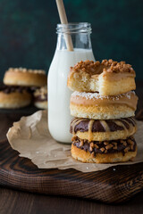 A stack of homemade donuts with a bite out of the top one and a bottle of milk.