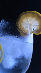 Copa de gin tonic con hielo y limón en un fondo negro