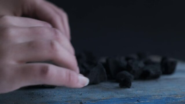 4k v&iacute;deo. Chica escogiendo y rechazando carb&oacute;n seg&uacute;n su calidad en un fondo oscuro y r&uacute;stico