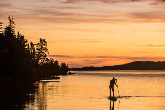 Man paddles at sunrise near Belle Isle on Isle Royale in Lake Superior, Michigan.