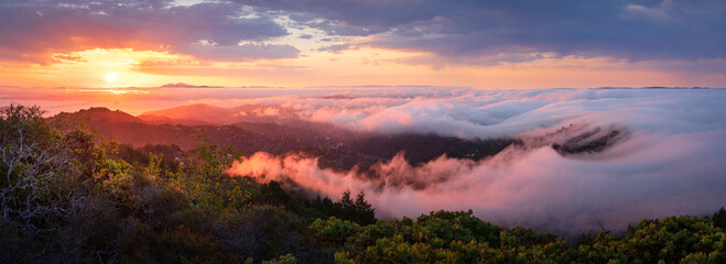 A colorful, dramatic sunrise over fog waves, viewed from Mt. Tamalpais, California.