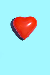Red heart balloon against bright blue background. Minimal love concept. 