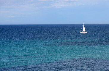 Lonely Sailing boat on blue open sea in Apulia, Italy. 