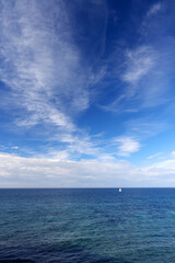 Naklejka na ściany i meble Lonely Sailing boat on blue open sea in Apulia, Italy. 