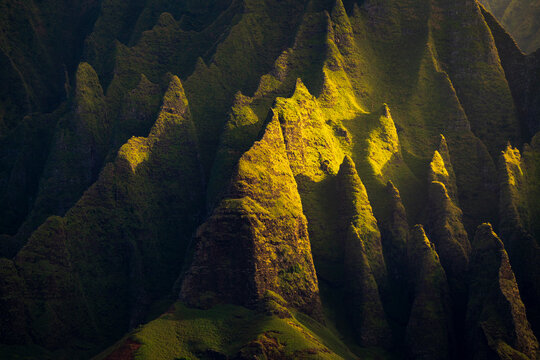 Golden light strikes the majestic features of the mountains along Kauai's Na Pali Coast.