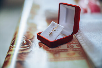 A little golden cross in a jewelry box prepared for a baby's christening baptism ceremony. High...