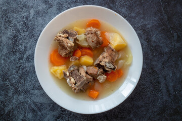 Boiled lamb meat with potatoes, carrots , onions, top view, copy space. Homemade winter comfort food.