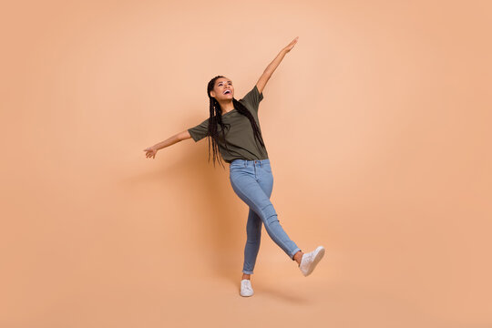 Full body photo of overjoyed cheerful person dancing raise hands toothy smile isolated on beige color background