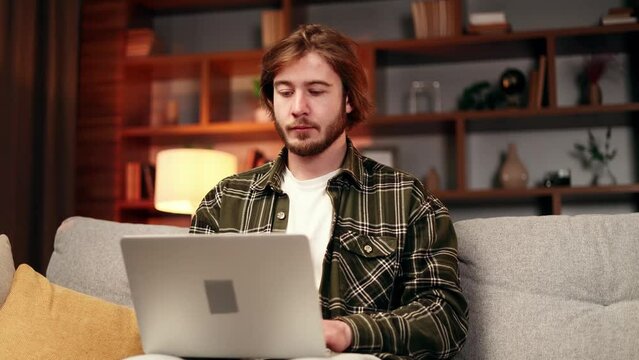 Smiling handsome freelancer with hands behind head feels satisfied with work well done at home Young bearded relax after hard remote distance working day finished project on laptop computer 