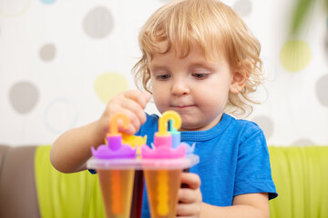 Child making ice cream from fruit juice on table at home