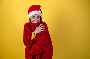 Young positive woman in christmas santa hat isolated on yellow background. Happy young woman in Santa's helper hat.