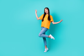 Fototapeta na wymiar Full body photo of cute brunette lady dance wear orange t-shirt jeans shoes isolated on teal color background