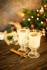 Two glasses of a traditional Christmas drink egg nog on wooden table