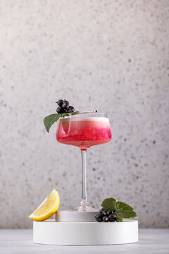 Elegant glass of Black Currant Gin Sour cocktail or mocktails surrounded by ingredients on gray table surface