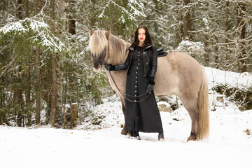 Woman dressed in black with light brown Icelandic horse.