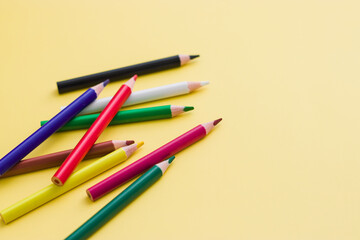 background from color pencils on yellow paper. Crayons - colored pencil set loosely arranged on yellow background. colored pencils are not arranged exactly in a row.