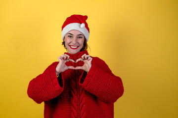 Young positive woman in christmas santa hat isolated on yellow background. Happy young woman in Santa's helper hat.