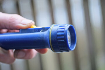 hand holding one blue plastic flashlight on gray background