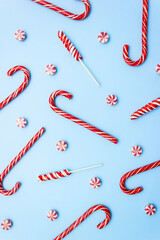 Candy canes, lollipops and striped candies on light blue backdrop. Vertical Christmas background. Selective focus.