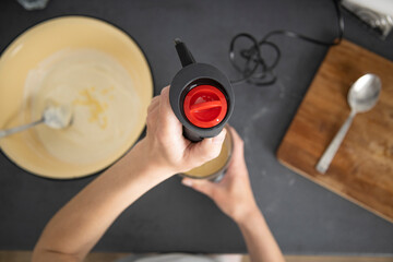 Fototapeta na wymiar Woman whipping dough for baking with a mixer. Top view, flat lay