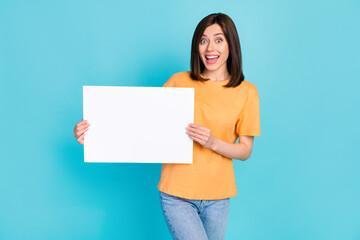 Fototapeta na wymiar Photo of adorable satisfied impressed girl dressed yellow t-shirt hands hold placard banner isolated on turquoise color background
