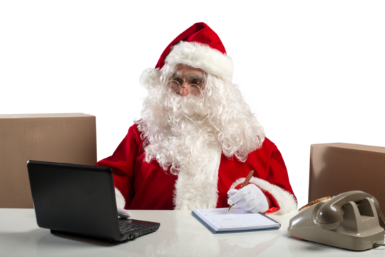 santa claus works in office with laptop and phone