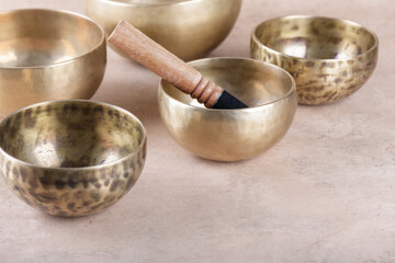 Tibetan singing bowls with sticks used during mantra meditations on beige stone background, copy...